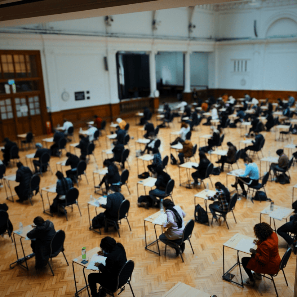 A photo of students sat in an exam hall taking an exam with their backs to the camera.